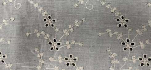Eyelet embroidery with small cut-work flowers and trailing stems.
