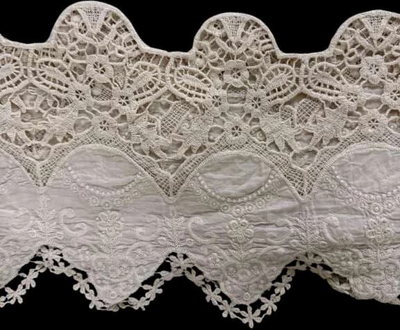 A scalloped cotton lace border with cut-work motifs.