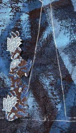 Blue dyed fabric with an appliquéd floral trail stitched over it.