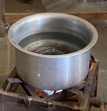 A steel pot heating on a small stove.