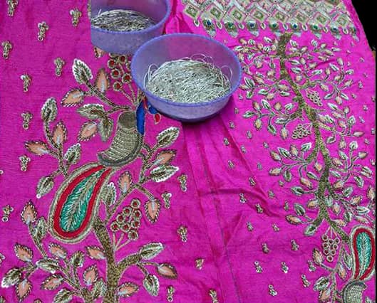 A magenta panel of metallic paisley embroidery with bowls of coiled dabka wire.