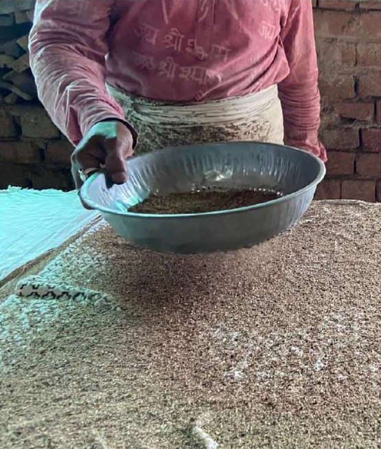 Sawdust sprinkled from a bowl over the wet mud resist.