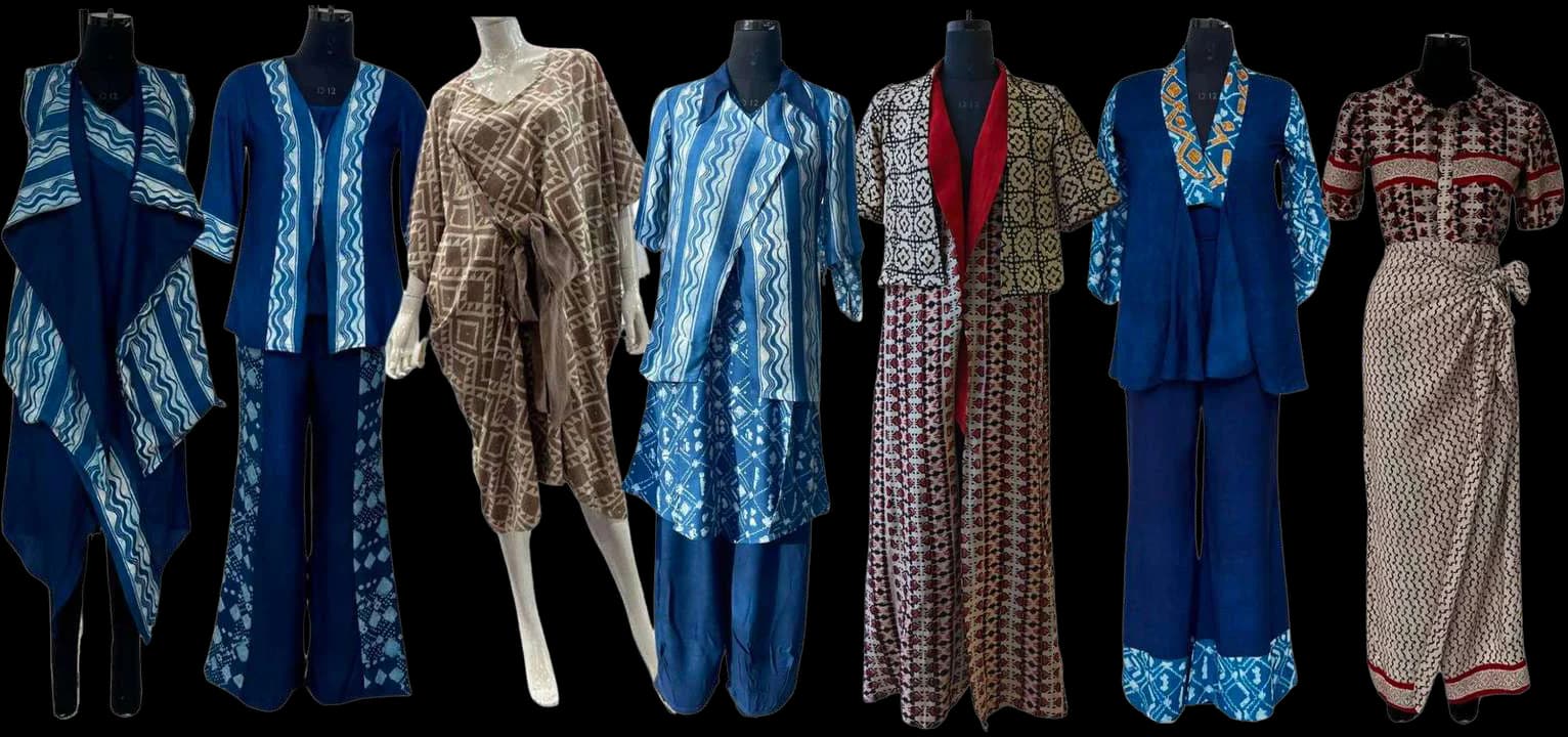 Seven garments on dress forms made from the Dabu and Bagru textiles: draped vests, jackets, flared trousers, a wrap dress and a wrap skirt in indigo, grey, brown and red prints.