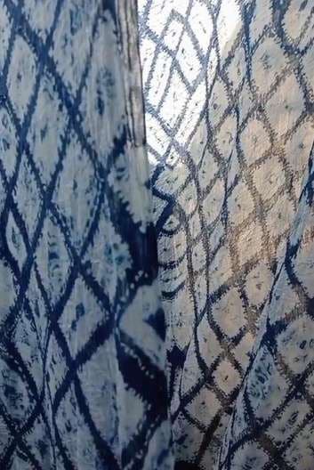 Blue diamond shibori hanging in front of a bright window.
