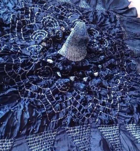 Indigo-dyed cloth still gathered and bound, stitches pulled tight.