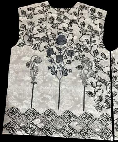 A vest panel printed with dark trees and flowers above a geometric border.